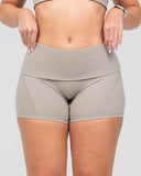 Person wearing beige athletic shorts on a plain background
