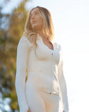 Woman wearing a white outfit with a blurred natural background