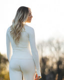 Woman wearing a white outfit standing outdoors with a blurred natural background