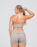 Woman wearing a gray sports bra and shorts set on a light gray background