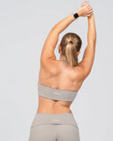 Person wearing a gray sports bra and leggings with a white background